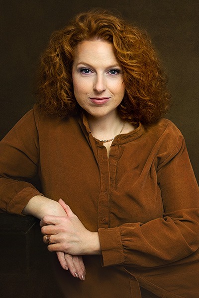 Eine Frau mit roten Locken sieht in die Kamera.