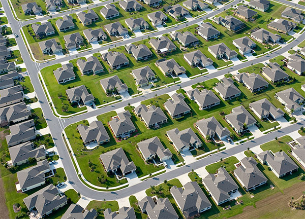 Luftaufnahme eines Wohngebiets mit Einfamilienhäusern und grünen Gärten, die eine ruhige Nachbarschaft zeigen.