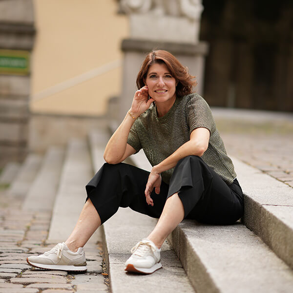 Eine Frau sitzt auf einer Treppe und lächelt in die Kamera