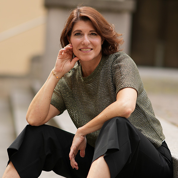 Eine Frau sitzt auf einer Treppe und lächelt in die Kamera