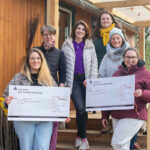 Eine Gruppe von Frauen, die eine Spende in Form eines riesigen Schecks übergeben