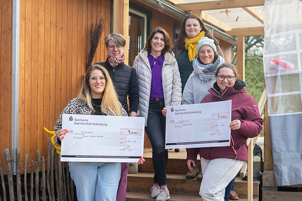 Eine Gruppe von Frauen, die eine Spende in Form eines riesigen Schecks übergeben