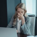 Eine Frau vor einem Laptop, die gestresst aussieht